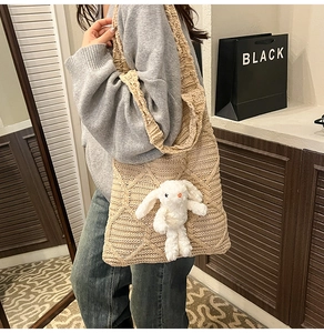 Close-up of beige crochet tote bag with textured knit pattern and plush rabbit charm