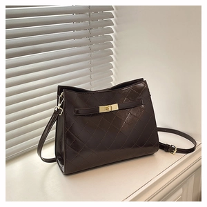 Detail of dark brown quilted crossbody bag with gold lock and adjustable strap