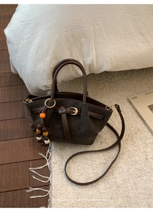 Détail d'un sac cabas dépoli marron foncé avec charme en perles et sangle en cuir