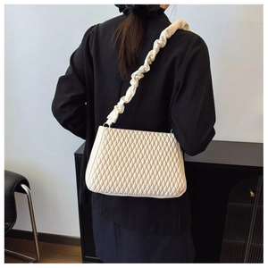 Detail of quilted beige shoulder bag featuring a unique gathered ruched strap design