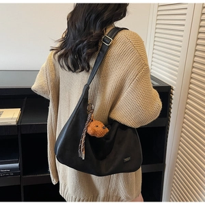 Détail du grand sac cabas noir avec un pendentif ours et une sangle en ruban rayé