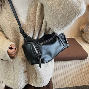 Detail of black cylindrical crossbody bag with functional zippers and slim leather strap