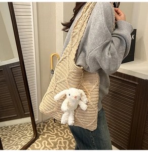 Close-up of beige crochet tote bag featuring diamond knit patterns and rabbit pendant