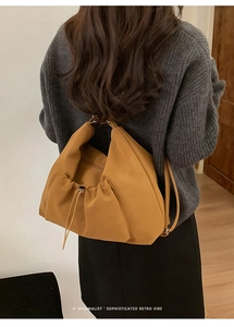 Minimalist ginger yellow cloud bag with drawstring pleats worn over the shoulder