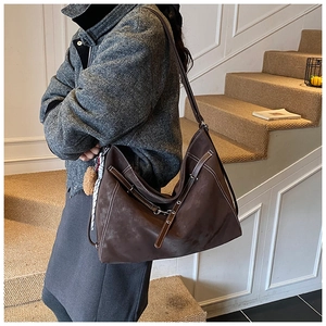 Detail of dark brown tote bag with suede texture and visible stitching on model