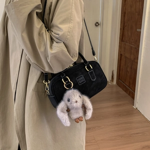 Detail of black suede pillow bag with embossed logo and cute grey rabbit plush charm