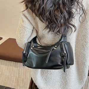 Close-up of black hobo bag with decorative silver zippers and long leather pullers