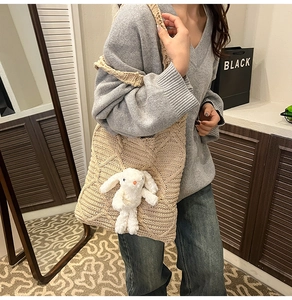 Detailed texture of beige crochet knit tote bag with fluffy white bunny plush charm