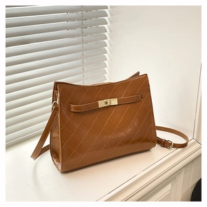 Detailed view of a brown quilted leather underarm bag with a golden turn-lock closure