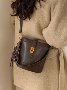Retro dark brown matte leather bucket bag for women with gold clasp and decorative pendant