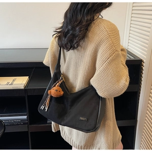Vista dettagliata della borsa hobo nera con texture opaca e ciondolo a forma di orso