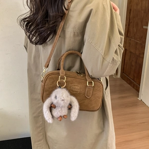 Detail of brown faux suede Boston bag with gold hardware and plush rabbit charm