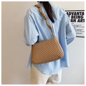 Close-up of caramel quilted shoulder bag with unique pleated strap and rhombic stitching
