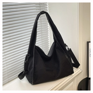 Macro shot of black oversized tote bag showing textured canvas and metal buckle details