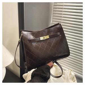 Detail shot of vintage dark brown quilted leather handbag with gold metal clasp and fine strap