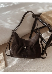 Detail of dark brown hobo shoulder bag with pleated front pocket and silver drawstring buckle