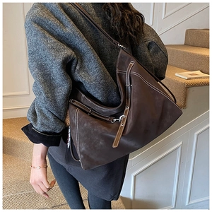 Close-up of vintage brown suede tote with white stitching and silver buckle detail