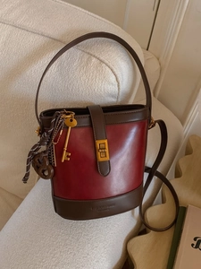 Vintage red and brown leather bucket bag with gold hardware on a cream sofa