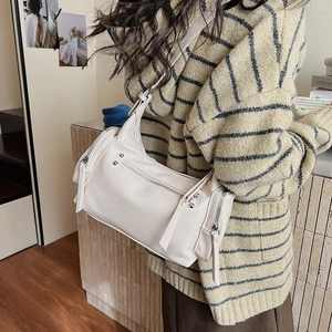 Detail of cream white PU shoulder bag with silver zipper and rivet on a crossbody model