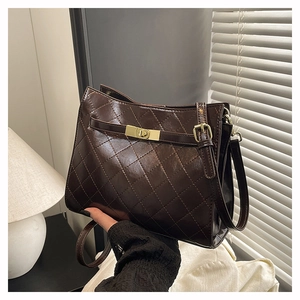 Close-up of dark brown quilted underarm bag with gold metal twist lock and fine stitching