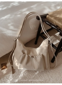 Detailed macro of beige faux leather handbag featuring drawstring pocket and soft texture