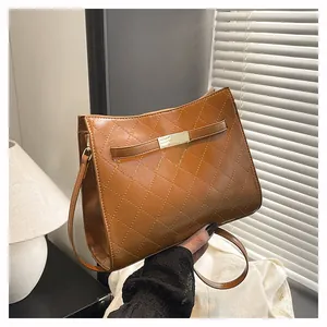 Detailed macro view of brown quilted faux leather shoulder bag with gold metal buckle