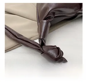 Detail showing knotted shoulder strap and glossy brown faux leather texture on tote bag