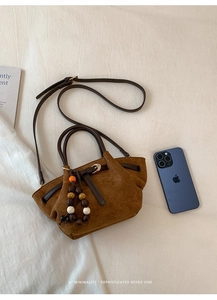 Detail view of a brown frosted tote bag with wooden beads and leather drawstring