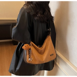 Détail du sac vintage marron avec daim, breloque d'ours en peluche et décor de gland