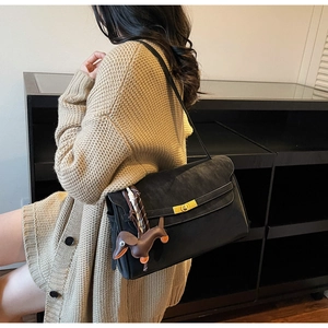 Detail of black matte tote bag with golden twist lock and cute brown puppy pendant