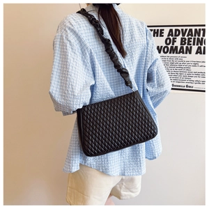 Detail of black quilted shoulder bag with unique ruched cloud-style strap and matte finish