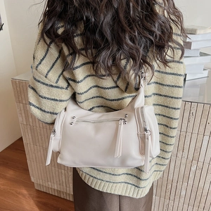 Detail of off-white shoulder bag with multiple zip pockets and stylish long tassels