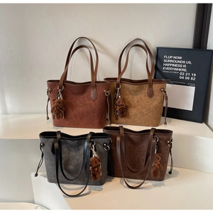 Detailed close-up of four embossed tote bags in earth tones with plush bear charms