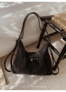 Detail of black leather hobo bag with drawstring buckle pocket on a retro chair