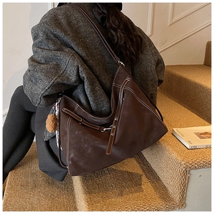 Detail of vintage brown tote bag with white contrast stitching and plush ball charm