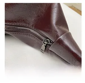 Close-up of the smooth metal zipper and pleated leather texture on dark brown bag