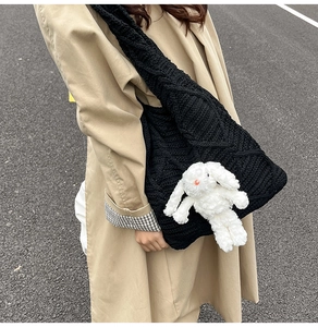 Close-up of black knit tote bag with a cute white plush bunny doll accessory