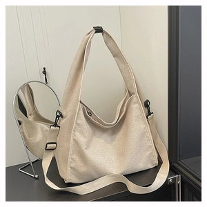 Detail view of large cream canvas hobo bag with wide strap and black buckle in mirror reflection