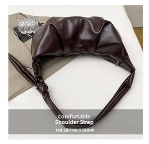 Detail of comfortable shoulder strap with knotted design on brown pleated bag