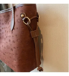 Detailed view of brown embossed tote bag featuring elegant golden hardware and motifs