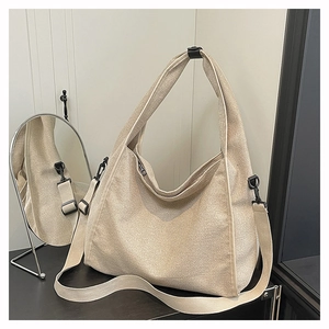 Detail of minimalist beige canvas hobo bag with wide strap and matte black hardware