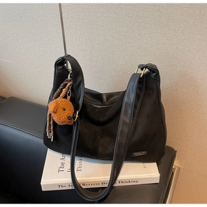 Dettaglio della borsa hobo in camoscio nero con logo lucido e ciondolo a orsetto