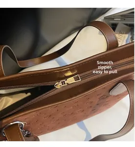 Detailed close-up showing the smooth golden zipper closure of the embossed tote bag