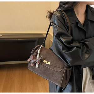 Detail of a brown retro tote bag with golden twist lock and a dachshund leather charm