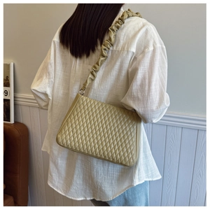 Detail of khaki quilted shoulder bag with ruched strap and elegant diamond stitching