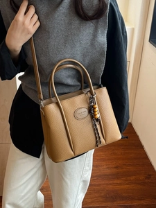Brown litchi grain leather bucket handbag with brand logo and wooden bead tassel