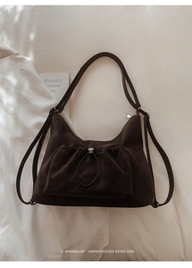 Close-up of a minimalist dark brown suede Hobo bag with drawstring pockets on white fabric
