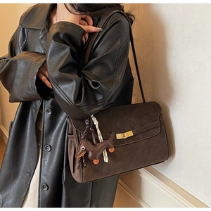 Detail of dark coffee tote bag with golden twist lock and brown dachshund leather charm