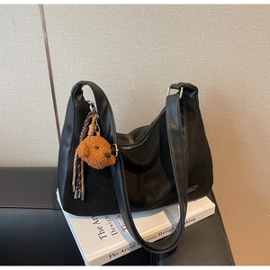Dettaglio borsa tote in ecopelle nera con ciondolo a forma di cucciolo di cane marrone