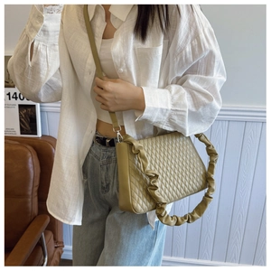 Detail of mustard yellow quilted handbag with trendy ruffled cloud-style shoulder strap
